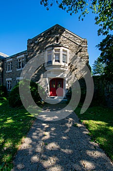 A Cobblestone Church With a Red Door And a Path Leading Up To It On a Clear Blue Sky