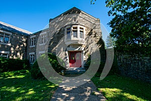 A Cobblestone Church With a Red Door And a Path Leading Up To It On a Clear Blue Sky