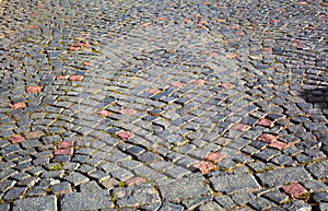 Cobblestone dark stone covering of the city square with patches of red stone