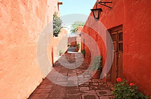Cobblestone path among red and orange color old buildings in the Monastery of Santa Catalina, Arequipa, Peru