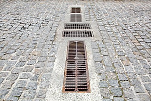 Cobblestone road of granite stone with drainage grates.