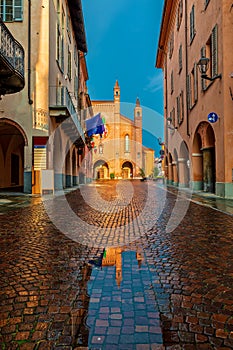 Cobblestone street and San Lorenzo cathedral in Alba, Italy.