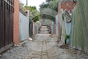A coble stone alley in suburban melbourne with an old iron fence