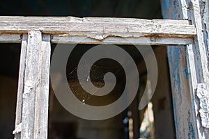 Cobweb in an old window frame. Abandoned house in the village. Broken window