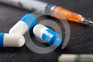Cocaine or other illegal drugs, white powder, money, pills, syringe on black background