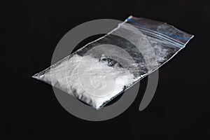 Cocaine in plastic packet on black background, closeup