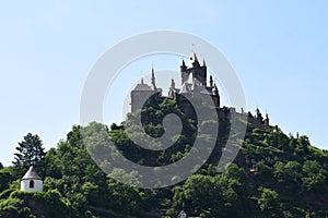 Cochem, Germany - 06 17 2021: Reichsburg with the small white chapel below