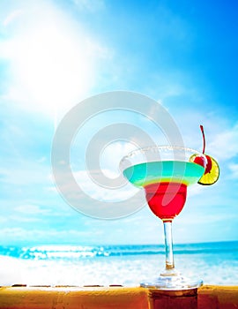 Cocktail on beach, blue sea and sky background