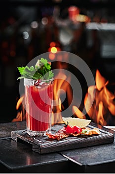 Cocktail Bloody Mary in a beautiful glass on copper designer bar counter, the background of real fire. Series of photo.