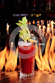 Cocktail Bloody Mary in a beautiful glass on copper designer bar counter, the background of real fire. Series of photo.