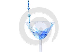Cocktail with blue liquid in glass. Glass with blue water pouring with liquid with splashes and drops. Martini glass filling with