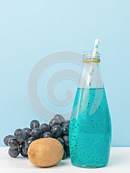 A cocktail bottle with basil seeds with a cocktail tube on a blue background