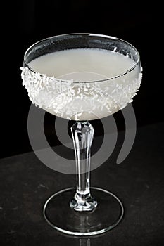 cocktail of coconut and ice. Macro, black background, hand, white photo