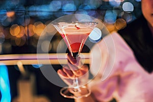 cocktail cosmopolitan in woman hand with bokeh