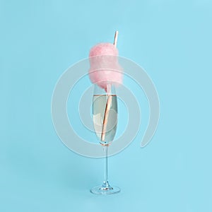 Cocktail with cotton candy in glass on blue background