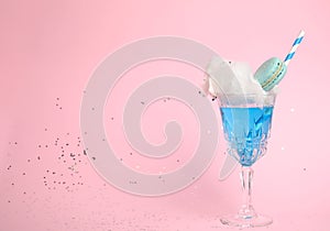 Cocktail with cotton candy in glass on pink background
