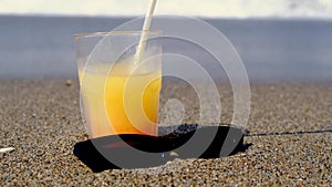 Cocktail drink on the beach. Sunglasses, holiday, relaxed. Close up glass of smoothie juice and sunglasses on sand at