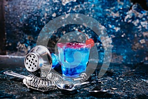 Cocktail drink with blue curacao and cherry served at bar