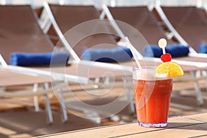 Cocktail with fruits in glass near beach armchair