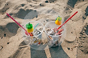 Cocktail with garbage and tropical decor on clean beach. Plastic ocean pollution, environmental crisis. Say no plastic. Single-use