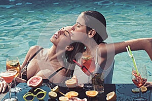 Cocktail at girls in pool on maldives. Summer vacation and swimming at sea. Fashion women with refresh alcohol and fruit