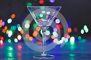 Cocktail glass on defocused garland colorful lights. What to drink on christmas party. Alcohol cocktail for winter party