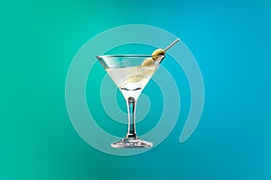 Cocktail glass with dry martini with olives isolated over gradient blue green color background in neon.