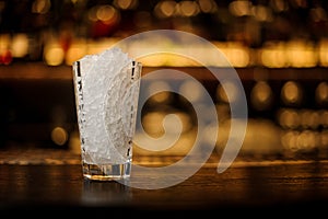 Cocktail glass filled with ice cubes on the bar counter of restaurant