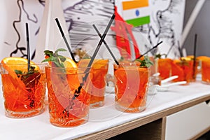 Cocktail glass with orange slices and mint leaves with black cocktail straws