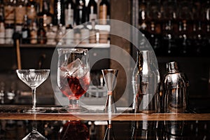 Cocktail glasses filled with alcoholic drink and bar equipment arranged on the bar counter