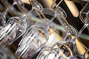 Cocktail Glasses hanging above the bar in the restaurant. Empty glasses for wine. Wine glasses in shelf above a bar rack in