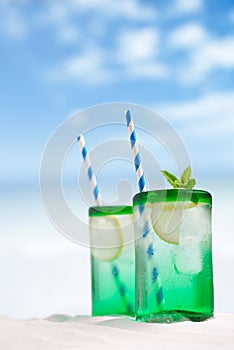 Cocktail with ice, rum, lemon and mint in a glass on beach