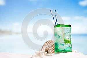 Cocktail with ice, rum, lemon and mint in a glass on beach