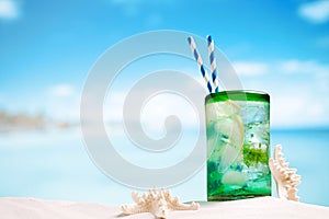 Cocktail with ice, rum, lemon and mint in a glass on beach