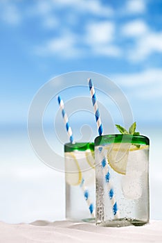 Cocktail with ice, rum, lemon and mint in a glass on beach