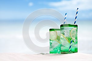 Cocktail with ice, rum, lemon and mint in a glass on beach