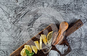 Cocktail ingredient: Summer mint and lemon for refreshing cocktail mojito with ice on kitchen board.