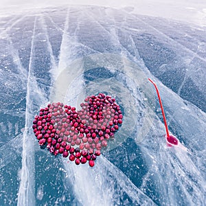 Cocktail kiss winter of lake Baikal with straw and hole in pure ice with cranberry heart, top view