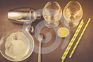 Cocktail making bar tools/ Cocktail shaker, two glass lime and straws on a dark background. Top view and copyspace