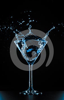 Cocktail martini glass splash on black background