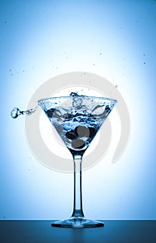 Cocktail martini glass splash on white and blue gradient background