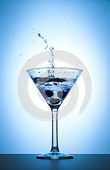 Cocktail martini glass splash on white and blue gradient background