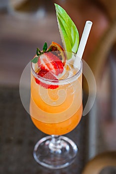 Cocktail of orange juice in glass with strawberries and apple, selective focus