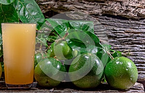 Cocktail and passion fruit juice Passiflora edulis Sims and fresh green fruits on a woody background