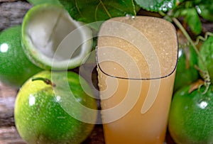 Cocktail and passion fruit juice Passiflora edulis Sims and fresh green fruits on a woody background