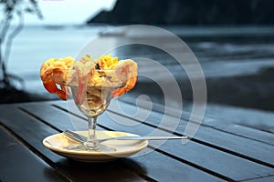 Cocktail salad with shrimp and seafood on a wooden table against the background of the sea