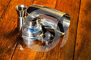 Cocktail shaker accessories and shots glasses on a wooden board. Bar utensils, drinks concept