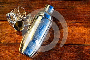 Cocktail shaker accessories and shots glasses on a wooden board. Bar utensils, drinks concept