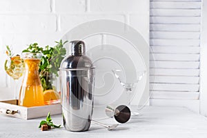 Cocktail shaker, swizzle, tongs and spoon with ice in a bucket for preparing a summer cocktail