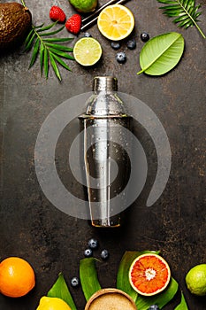 Cocktail shaker, tropical fruits and leaves on a dark background